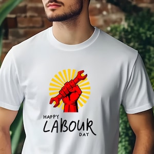 May include: White t-shirt featuring a red fist holding a wrench, set against a yellow sunburst design. The text "HAPPY LABOUR DAY" is printed below in black. The shirt is a crew neck style.