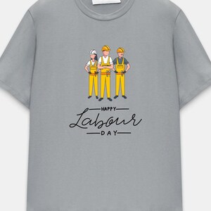 May include: A light gray t-shirt featuring a graphic of three construction workers in yellow overalls and hard hats. The text "Happy Labour Day" is written in a stylish script below the graphic.