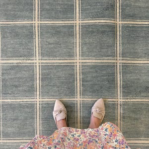 Peut inclure: Un tapis à carreaux bleu et blanc avec un motif quadrillé. Le tapis a un aspect texturé. Des chaussures beiges avec des nœuds sont visibles, ainsi qu'une jupe à motifs floraux.
