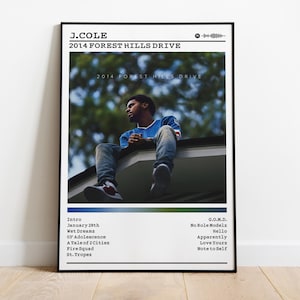 Könnte beinhalten: Gerahmtes Poster mit J. Coles Album "2014 Forest Hills Drive". Das Bild zeigt einen Mann, der auf einem Dach sitzt. Das Poster enthält den Albumtitel, den Künstlernamen und eine Titelliste. Das Farbschema ist hauptsächlich blau, grün und weiß.