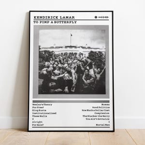 May include: Black and white framed poster featuring the album cover for Kendrick Lamar's "To Pimp a Butterfly." The image shows a group of people in front of a building. The poster includes the album title, artist name, and tracklist.