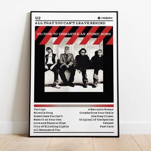 Pode incluir: Pôster emoldurado em preto com a banda U2. O pôster inclui o título do álbum "All That You Can't Leave Behind" e os membros da banda. O pôster também lista os títulos das músicas do álbum.