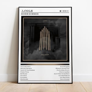 Könnte beinhalten: Ein gerahmtes Poster mit dem Albumcover von J. Coles "Born Sinner". Das Kunstwerk ist ein dunkles, stimmungsvolles Bild mit vertikalen goldenen Linien auf schwarzem Hintergrund. Das Poster enthält den Albumtitel, den Künstlernamen und die Titelliste.