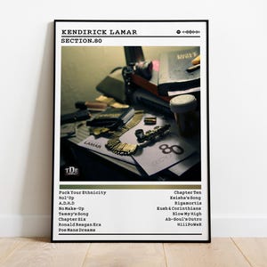 May include: Black framed poster featuring Kendrick Lamar's album "Section.80." The poster includes the album title, tracklist, and a photograph of items on a table. The album cover art is visible on the poster.