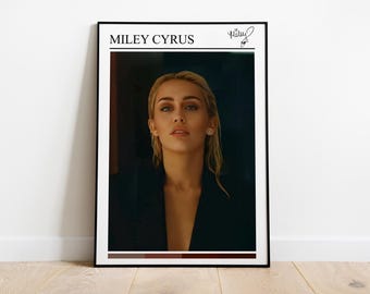 Könnte beinhalten: Gerahmtes Poster mit Miley Cyrus. Das Poster hat einen schwarzen Rahmen und einen weißen Rand. Das Bild zeigt ein Porträt von Miley Cyrus mit blonden Haaren und einem schwarzen Blazer. Der Text "MILEY CYRUS" steht oben, mit einer Unterschrift.
