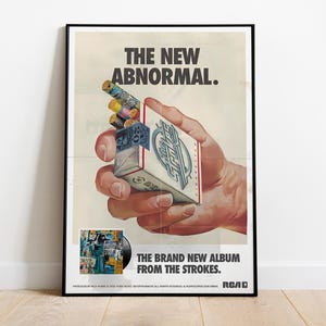 May include: Poster with the text "THE NEW ABNORMAL" above a hand holding a cigarette pack. The pack is branded "The Strokes." The poster also states "THE BRAND NEW ALBUM FROM THE STROKES."