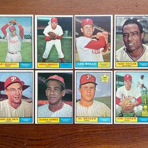 Könnte beinhalten: Eine Sammlung von acht Vintage-Baseballkarten der Philadelphia Phillies, angeordnet in zwei Reihen. Jede Karte zeigt einen Spieler in Teamuniform, darunter Art Mahaffey, Robin Roberts, Lee Walls, Tony Taylor, Bobby Gene Smith, Ruben Gomez, Al Neiger und Jim Coker, mit ihren Namen und Positionen am unteren Rand.