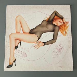 May include: Illustration of a woman with red hair wearing a sheer black bodysuit and black high heels, reclining on a car outline. The artwork has a vintage pin-up style, with a focus on the figure's pose and the car's design.