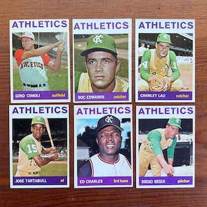 May include: Six vintage baseball cards featuring Athletics players. Each card has a player's image, name, and position. The cards are rectangular with a white border and the word "ATHLETICS" at the top.