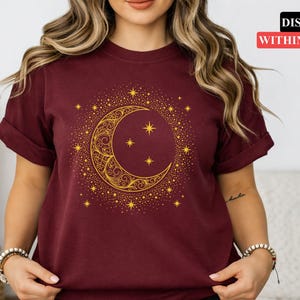 Op de afbeelding: Bordeauxrood t-shirt met een gouden maan- en sterrenontwerp. De maan heeft een sierlijk patroon, omringd door kleinere sterren. De tekst "DISPATCH WITHIN 24 HOURS" wordt weergegeven in een rode banner.