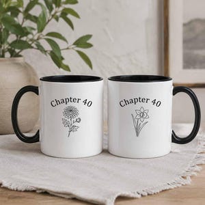 Peut inclure: Deux tasses en céramique blanche avec des anses et des bords noirs. Chaque tasse présente le texte noir "Chapter 40" imprimé au-dessus d'une illustration florale en trait noir. L'une affiche un chrysanthème, l'autre une jonquille.