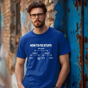 May include: A royal blue short-sleeved t-shirt featuring a white graphic print of a flowchart titled HOW TO FIX STUFF. The diagram outlines decision paths for fixing items, including text labels for YES, NO, SHOULD IT, FIXED IT, GAFFER TAPE, and WD-40.