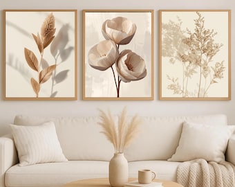 Peut inclure: Trois impressions d'art botanique encadrées. Les impressions présentent des fonds beiges avec des illustrations de plantes dans des tons bruns. L'œuvre est exposée au-dessus d'un canapé blanc avec des coussins et un vase de pampas.