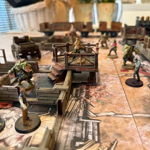 Puede incluir: Una escena de juego de mesa con figuras en miniatura y terreno. La escena incluye una plataforma de madera, vagones de tren en miniatura y varias figuras, incluyendo zombis y otros personajes de fantasía. El tablero de juego tiene una apariencia detallada y envejecida.