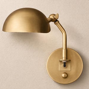 Puede incluir: Una lámpara de pared de latón con una pantalla semicircular. La lámpara tiene un brazo ajustable y una base circular. El diseño es simple y elegante, adecuado para varios estilos de interior. La lámpara es de metal y tiene un aspecto cálido y acogedor.