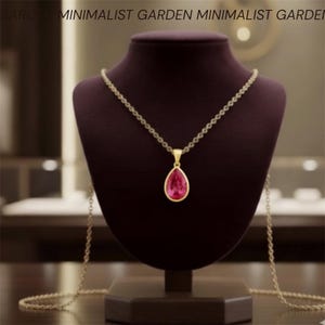 Könnte beinhalten: Eine goldfarbene Halskette mit einem tropfenförmigen, rosa Edelsteinanhänger. Die Halskette wird auf einer dunkelvioletten Schmuckbüste präsentiert. Die Worte "MINIMALIST GARDEN" befinden sich oben im Bild.