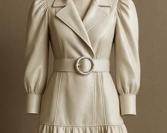 May include: A cream-colored dress with a tailored silhouette. The dress features a notched collar, long sleeves with puffed shoulders, and a belted waist with a silver-toned buckle. The skirt has a tiered, ruffled hemline. The dress is displayed on a mannequin.