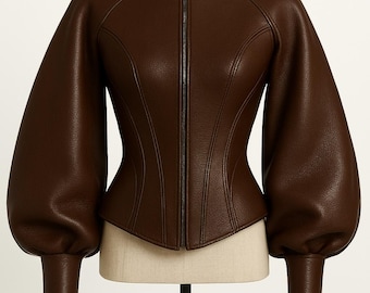 May include: A brown leather jacket with a high collar and a full-length zipper. The jacket features long, voluminous sleeves that taper to fitted cuffs. The tailored bodice has curved seams for a defined shape. The jacket is displayed on a mannequin.