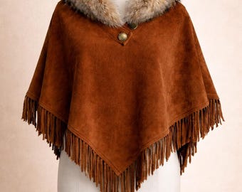 May include: A brown suede poncho with a faux fur collar and fringe trim. The poncho has a button closure at the neckline. The garment is displayed on a mannequin.