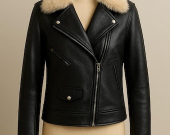 May include: Black leather jacket with a cream-colored fur collar and cuffs. The jacket features a diagonal zipper closure, a small pocket, and silver-tone hardware. The jacket is displayed on a mannequin.