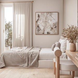 Può includere: Una camera da letto dai toni neutri con letto, scrivania e opere d'arte. Il letto è coperto da una coperta e cuscini beige. Una scrivania in legno con un vaso di fiori secchi e una sedia sono nell'angolo. Una grande opera d'arte astratta incorniciata è appesa al muro.