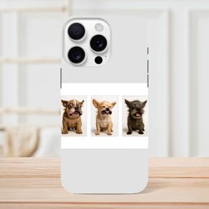 Puede incluir: Funda de teléfono blanca con una foto de tres perros pequeños con expresiones divertidas. Los perros son de color marrón claro, beige y gris oscuro. La funda tiene un módulo de cámara con tres lentes y un flash.