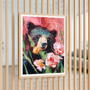 May include: A framed painting of a black bear surrounded by pink and yellow flowers. The bear's fur is dark, with a lighter muzzle. The background is a blend of pink and red hues, creating a vibrant and artistic piece.