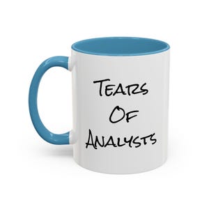 May include: White ceramic mug with a blue interior and handle. The mug has the text "Tears Of Analysts" in black, handwritten lettering. A humorous gift for analysts.
