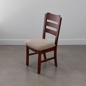 May include: A wooden dining chair with a dark brown finish. The chair has a padded seat with a beige patterned fabric. The backrest features a curved top and three horizontal slats. The chair is designed for indoor use.