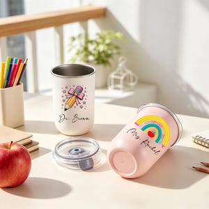 May include: Two insulated tumblers, one white and one pink, with teacher-themed designs. The white tumbler features a pencil and bow graphic with "Dr. Brown" text. The pink tumbler has a rainbow and apple graphic with "Mrs. Rachel" text. A red apple and pencils are also visible.