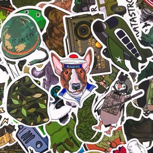 Puede incluir: Una colección de pegatinas coloridas con temas militares y animales. Incluye un bulldog con gorro de marinero con "MARINE", un pingüino con equipo táctico y un casco verde con el texto "IT AIN'T ME".