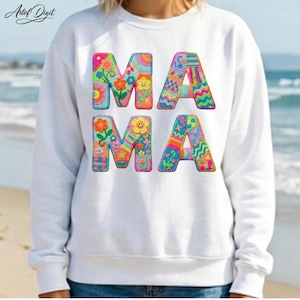 Peut inclure: Sweat-shirt blanc avec le mot "MAMA" en lettres brodées colorées. Chaque lettre est ornée de fleurs, de motifs et d'un visage de fleur souriant. Le sweat-shirt est porté sur une plage.