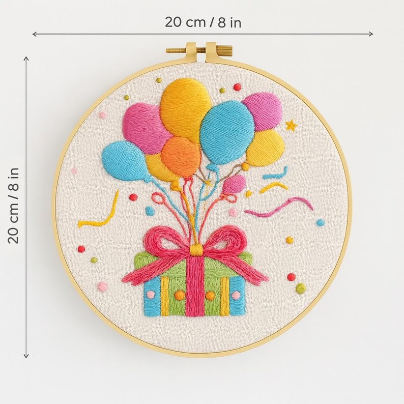 May include: Embroidered hoop art featuring a colorful birthday design. The artwork includes a gift box with a pink bow, balloons in various colors, and confetti. The hoop measures 8 inches (20 cm) in diameter.