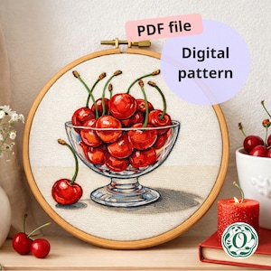 Op de afbeelding: Geborduurde afbeelding van rijpe rode kersen in een glazen kom. De borduurwerk is geplaatst tegen een neutrale stof, met de tekst "PDF file" en "Digital pattern" zichtbaar. Een kaars en kersen zijn op de achtergrond.