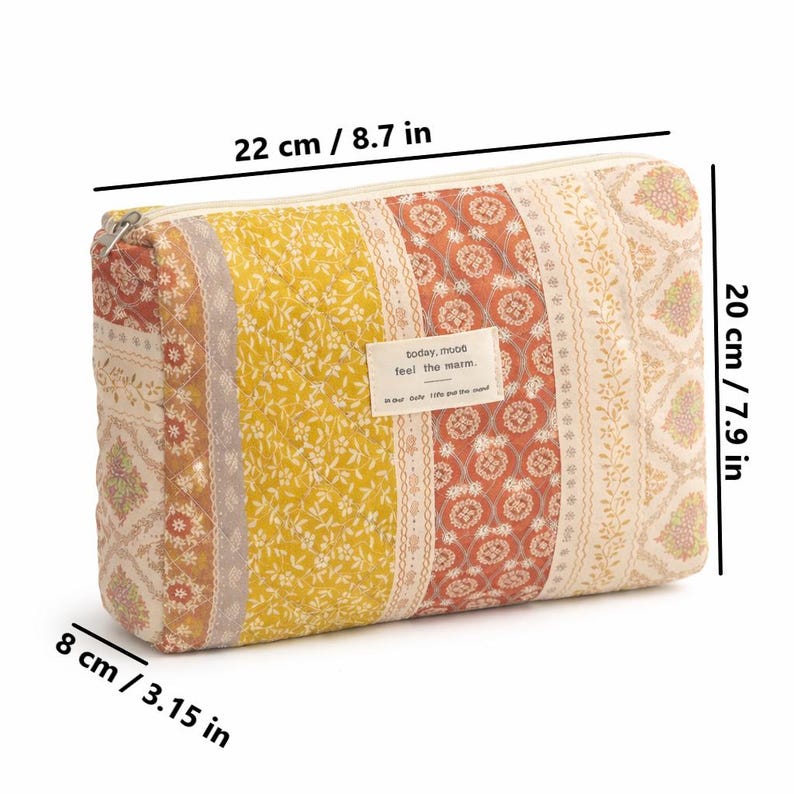 May include: A quilted cosmetic bag with a zipper closure, measuring 8.7 inches long, 7.9 inches high, and 3.15 inches wide. The bag features a patchwork design with floral and geometric patterns in yellow, orange, and cream colors. The text "today, mood feel the warm" is on a small label.