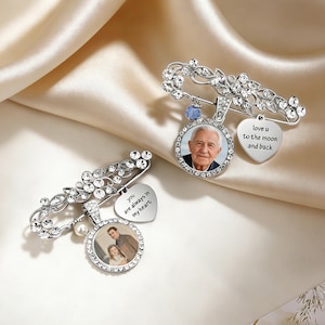 Può includere: Due spille d'argento con dettagli floreali e di cristallo. Ogni spilla presenta un ciondolo fotografico circolare e un ciondolo a forma di cuore con testo. Un ciondolo recita "love u to the moon and back", l'altro "you are always in my heart."