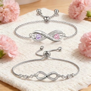Puede incluir: Dos pulseras plateadas con el símbolo del infinito y cierres ajustables. Una pulsera tiene el texto "Easter & Nance" y dos gemas en forma de corazón. La otra pulsera tiene el texto "Smith David" y un símbolo de corazón, con gemas claras.