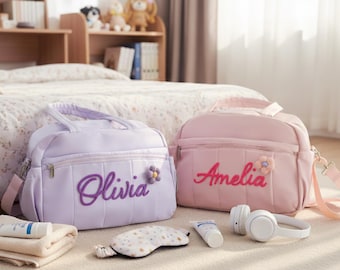 Puede incluir: Dos bolsas personalizadas, una lavanda y otra rosa, cada una con un nombre bordado en la parte delantera. La bolsa lavanda dice "Olivia" y la rosa "Amelia". Ambas bolsas tienen un adorno floral. Otros artículos incluyen auriculares, antifaz y productos para el cuidado de la piel.