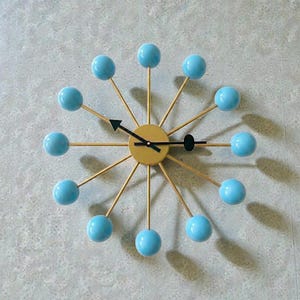 Reloj de pared moderno de mediados de siglo con diseño de estrella, decoración de pared azul y dorada, pieza decorativa minimalista para la sala de estar.