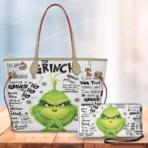 May include: A white tote bag and matching wallet featuring a green Grinch face and various Grinch-themed phrases in black. The tote bag has beige handles with red trim. The wallet has a wrist strap.