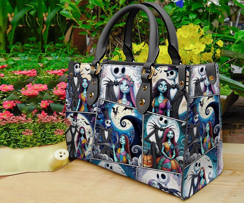 May include: A tote bag featuring a collage of images with characters from The Nightmare Before Christmas. The bag has black handles and gold-colored hardware. The background includes flowers and greenery.