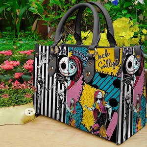 K&ouml;nnte beinhalten: Rechteckige Handtasche mit Patchwork-Design mit Jack Skellington und Sally aus The Nightmare Before Christmas. Die Tasche hat schwarz-wei&szlig; gestreifte Paneele, die Worte "Jack & Sally" und "Forever" und schwarze Griffe.