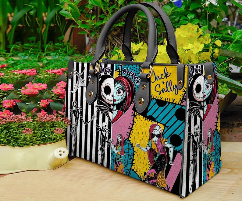 K&ouml;nnte beinhalten: Rechteckige Handtasche mit Patchwork-Design mit Jack Skellington und Sally aus The Nightmare Before Christmas. Die Tasche hat schwarz-wei&szlig; gestreifte Paneele, die Worte "Jack & Sally" und "Forever" und schwarze Griffe.