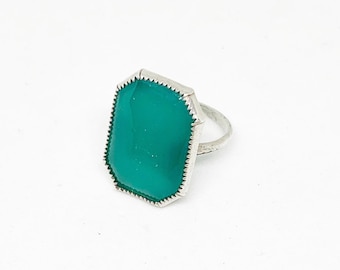 May include: A silver ring with a large, rectangular, teal-colored gemstone.