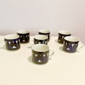 Peut inclure: Ensemble de six tasses à café en céramique blanche avec un motif géométrique noir et bleu. Les tasses ont une forme arrondie et une petite poignée.