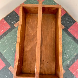 May include: A wooden tool caddy with a divided interior and a handle. The caddy is made of natural wood with a light brown finish.