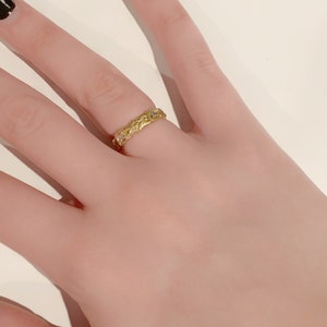 May include: A gold ring with a delicate floral design and small clear stones.