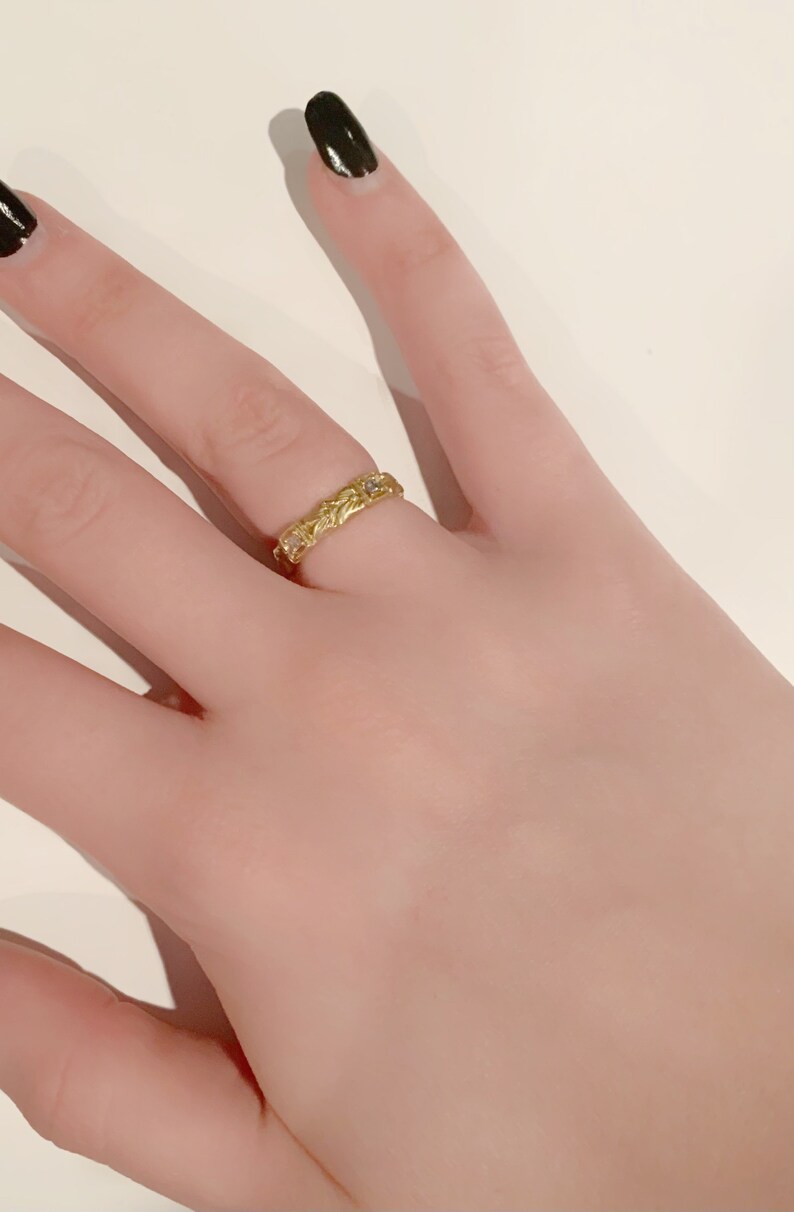 May include: A gold ring with a delicate floral design and small clear stones.