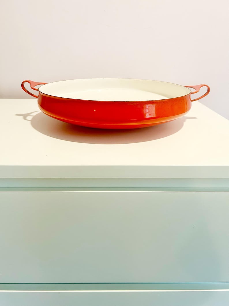 May include: Orange enamel cast iron serving dish with white interior and two handles.