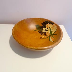 May include: A wooden bowl with a hand-painted design of flowers and leaves in shades of green, yellow, and orange.